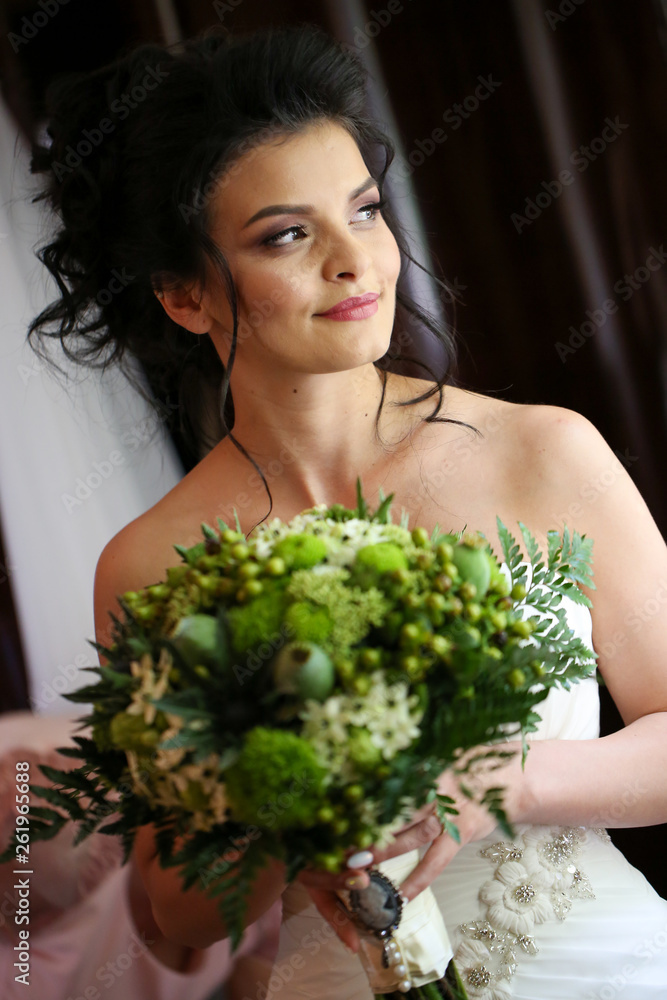 Beautiful brunette bride posing with bouquet of flowers in hands Beautiful brunette bride posing with bouquet of flowers in hands