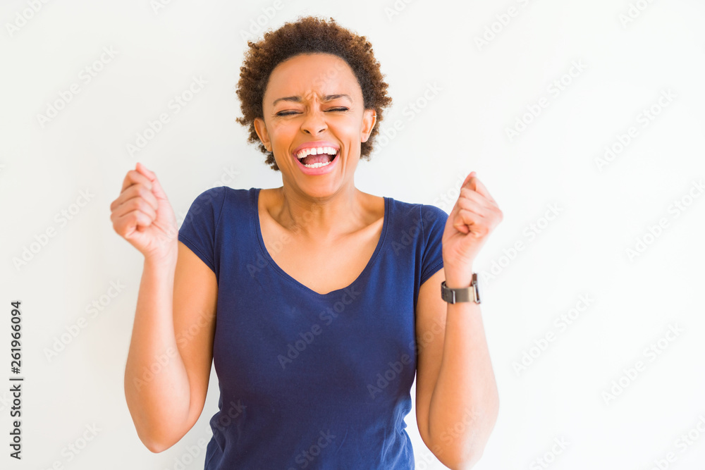 Young beautiful african american woman over white background excited for success with arms raised celebrating victory smiling. Winner concept. Young beautiful african american woman over white background excited for success with arms raised celebrating victory smiling. Winner concept.