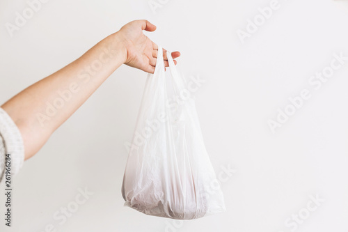 Ban single use plastic. Woman holding in hand groceries in plastic polyethylene bag. Zero Waste shopping concept.  Reuse, reduce, recycle, refuse. Choose eco natural bags
