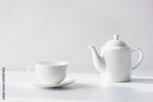 Set of white utensils for tea, white teapot and cup