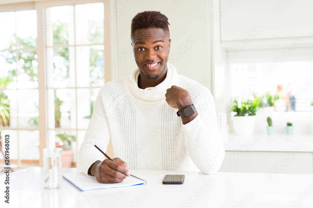 African american student man writing on a paper using a pencil with surprise face pointing finger to himself African american student man writing on a paper using a pencil with surprise face pointing finger to himself