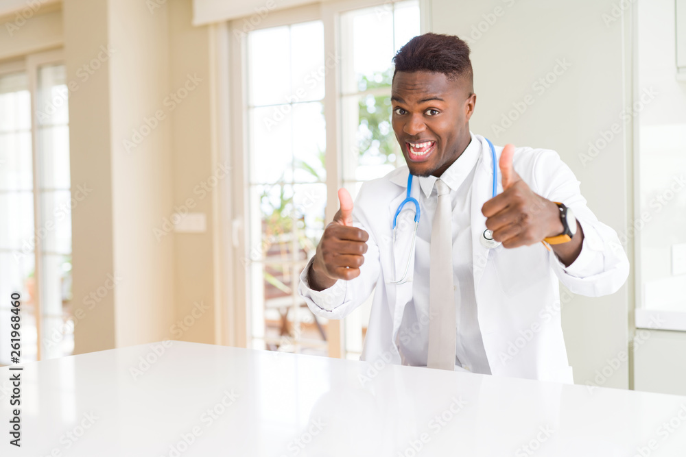 African american doctor man at the clinic approving doing positive gesture with hand, thumbs up smiling and happy for success. Looking at the camera, winner gesture. African american doctor man at the clinic approving doing positive gesture with hand, thumbs up smiling and happy for success. Looking at the camera, winner gesture.