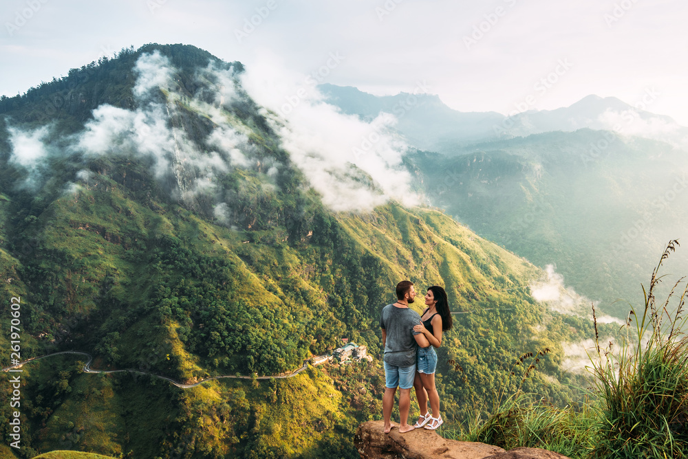 The couple greets the sunrise in the mountains. Man and woman in the mountains. Man and woman hugging. The couple travels around Asia. Travel to Sri Lanka. Serpentine in the mountains. Honeymoon