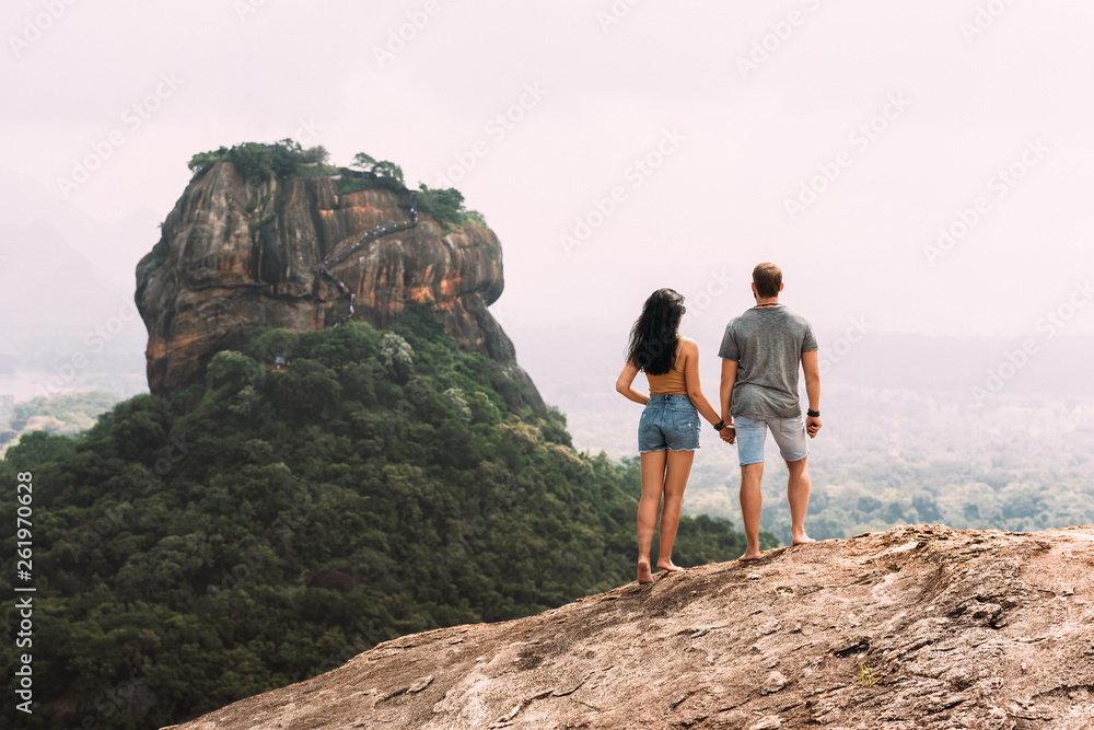 A couple in love on a rock admires the beautiful views. Boy and girl on the rock. A couple in love travels. Couple in Sri Lanka. Honeymoon in Asia. Man and woman in Sigiriya. Rear view pair