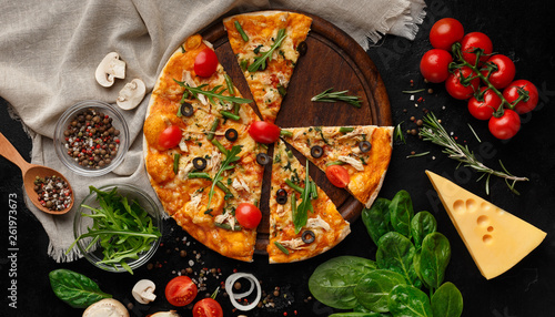 Hot pizza with tomatoes and herbs on cutting board