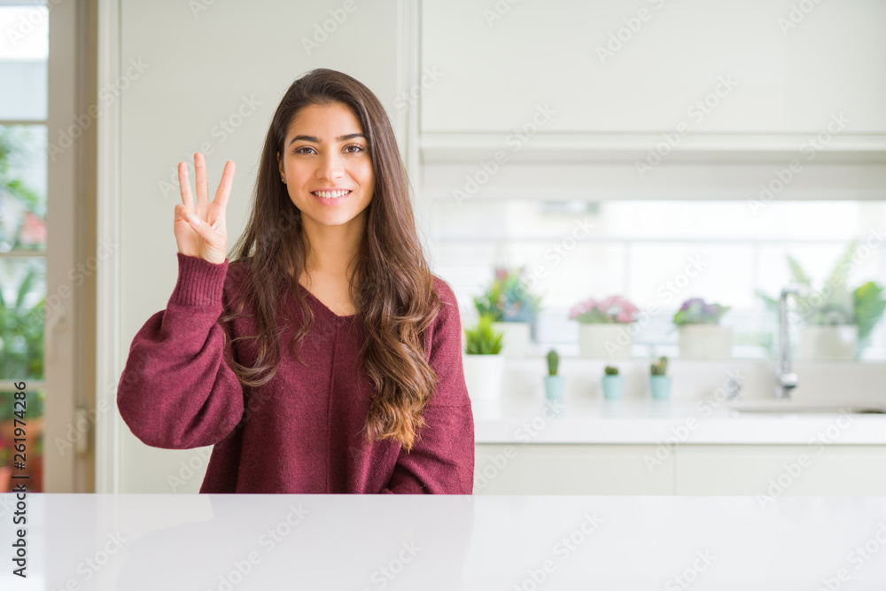 Young beautiful woman at home showing and pointing up with fingers number three while smiling confident and happy.
