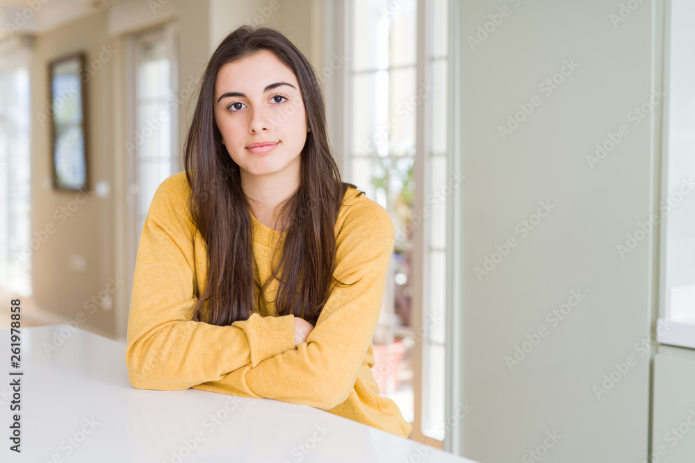 Beautiful young woman wearing yellow sweater with serious expression on face. Simple and natural looking at the camera. Beautiful young woman wearing yellow sweater with serious expression on face. Simple and natural looking at the camera.