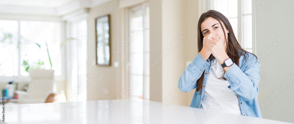 Wide angle picture of beautiful young woman sitting on white table at home Ready to fight with fist defense gesture, angry and upset face, afraid of problem Wide angle picture of beautiful young woman sitting on white table at home Ready to fight with fist defense gesture, angry and upset face, afraid of problem