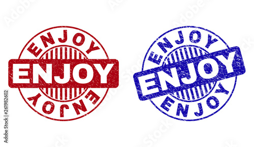 Grunge ENJOY round stamp seals isolated on a white background. Round seals with grunge texture in red and blue colors. Vector rubber imitation of ENJOY title inside circle form with stripes.