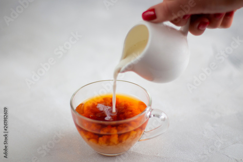 Pouring milk from the jug into a cup of black tea