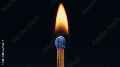 Macro shot of a wooden safety matchstick burning with a small bright flame.