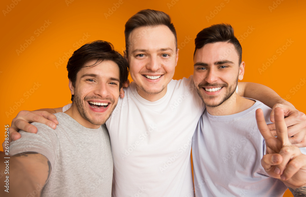 Obraz premium Portrait of cheerful guys making selfie, having fun