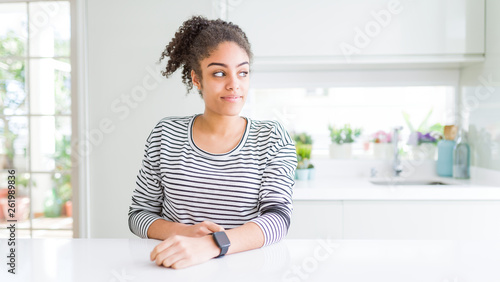 Beautiful african american woman with afro hair wearing casual striped sweater smiling looking to the side and staring away thinking.