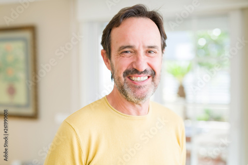 Handsome middle age man smiling looking at the camera at home