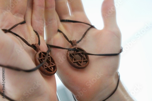 Man's hand holding a David Star or Magen David made of wood. The State of Israel, Judaism, Zionism concept image. Conversion to Judaism, giyur concept.