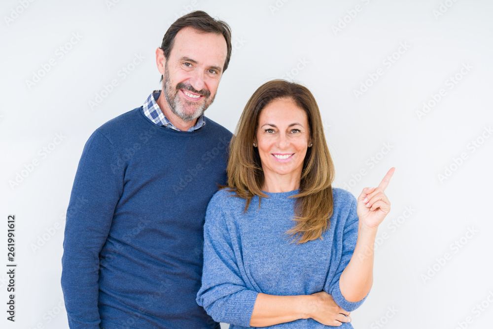 Beautiful middle age couple in love over isolated background with a big smile on face, pointing with hand and finger to the side looking at the camera. Beautiful middle age couple in love over isolated background with a big smile on face, pointing with hand and finger to the side looking at the camera.