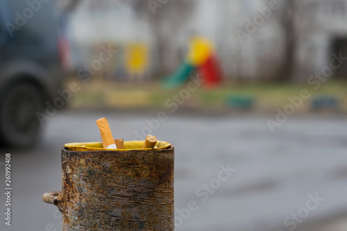 cigarette butts are stored in a pipe of a column of a protection for the Parking which is about the road in the background a Playground photo