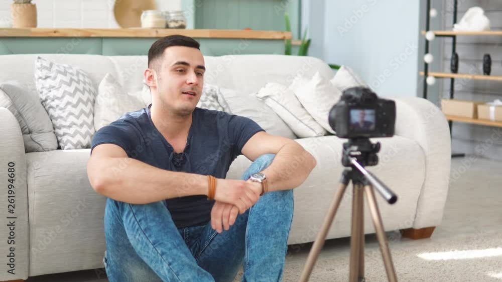 Young male blogger talking on digital camera recording video vlog at home Young male blogger talking on digital camera recording video vlog at home