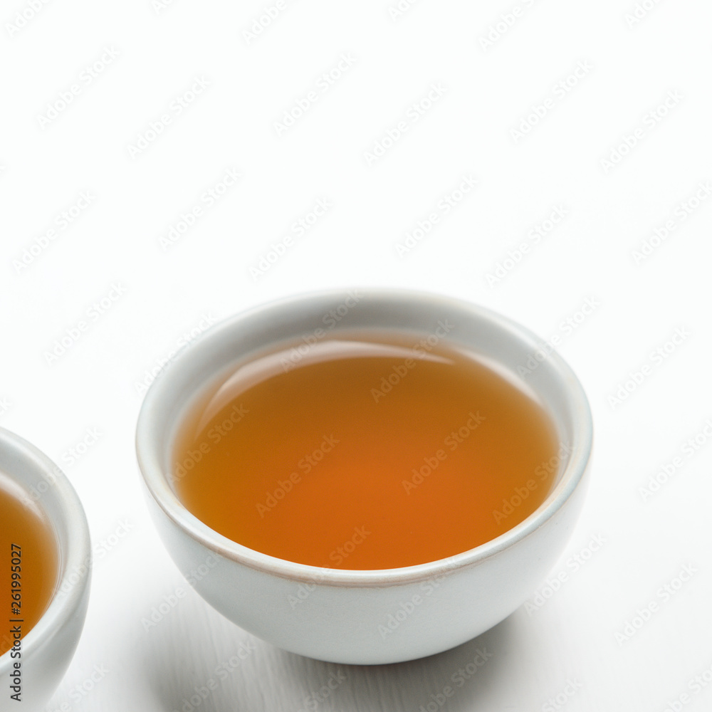 A small cup with brewed green tea on a white background. Minimal composition. Concept useful refreshing natural diet drink A small cup with brewed green tea on a white background. Minimal composition. Concept useful refreshing natural diet drink
