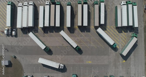 Buildings of logistics center, warehouses near the highway, truck parking process, view from height, a large number of trucks in the parking lot near warehouse.
