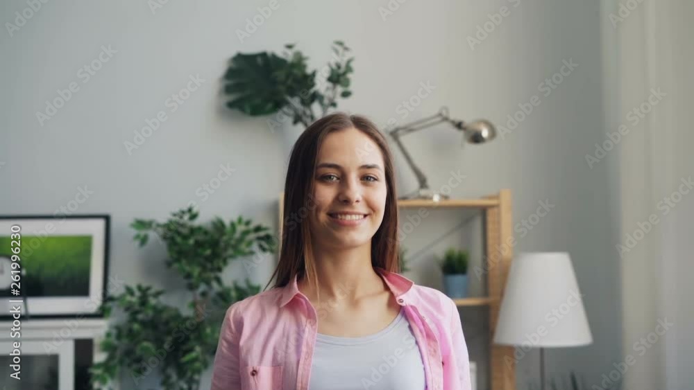 Slow motion portrait of beautiful young girl in modern apartment smiling and looking at camera. Attractive people, positive emotios and interior concept. Slow motion portrait of beautiful young girl in modern apartment smiling and looking at camera. Attractive people, positive emotios and interior concept.