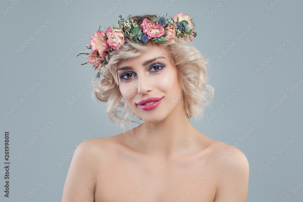 Fashion model with flowers. Cheerful blonde woman with short haircut and makeup on blue background