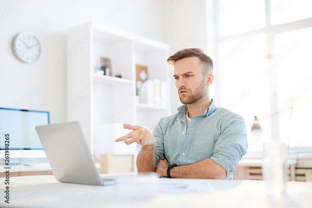 Portrait of puzzled man pointing at laptop screen with questioning look , copy space Portrait of puzzled man pointing at laptop screen with questioning look , copy space