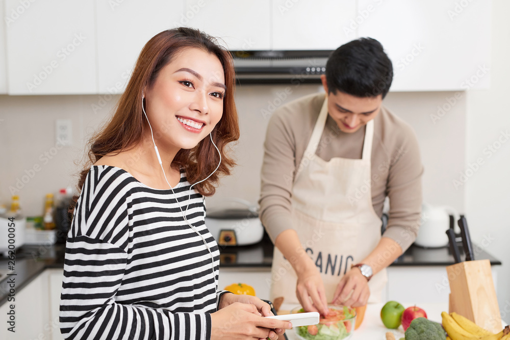 Φωτογραφία Portrait of a pretty young couple cooking salad together according to a recipe o