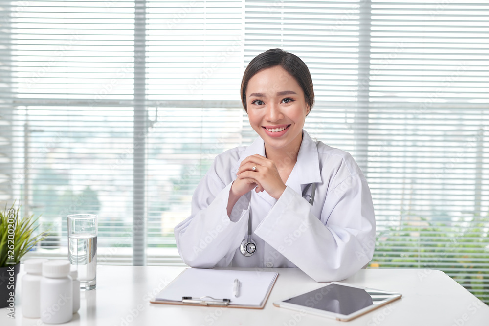 Female doctor working at office desk and smiling at camera Female doctor working at office desk and smiling at camera