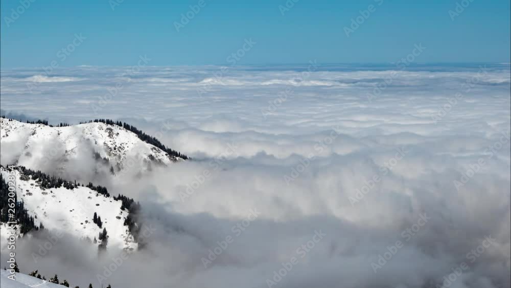 The movement of a dense layer of clouds above the ground. Mountains sprout from the clouds that cover the earth. Time laps The movement of a dense layer of clouds above the ground. Mountains sprout from the clouds that cover the earth. Time laps