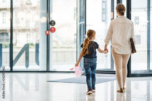 Photography A rear view of businesswoman with small daughter walking in office building
