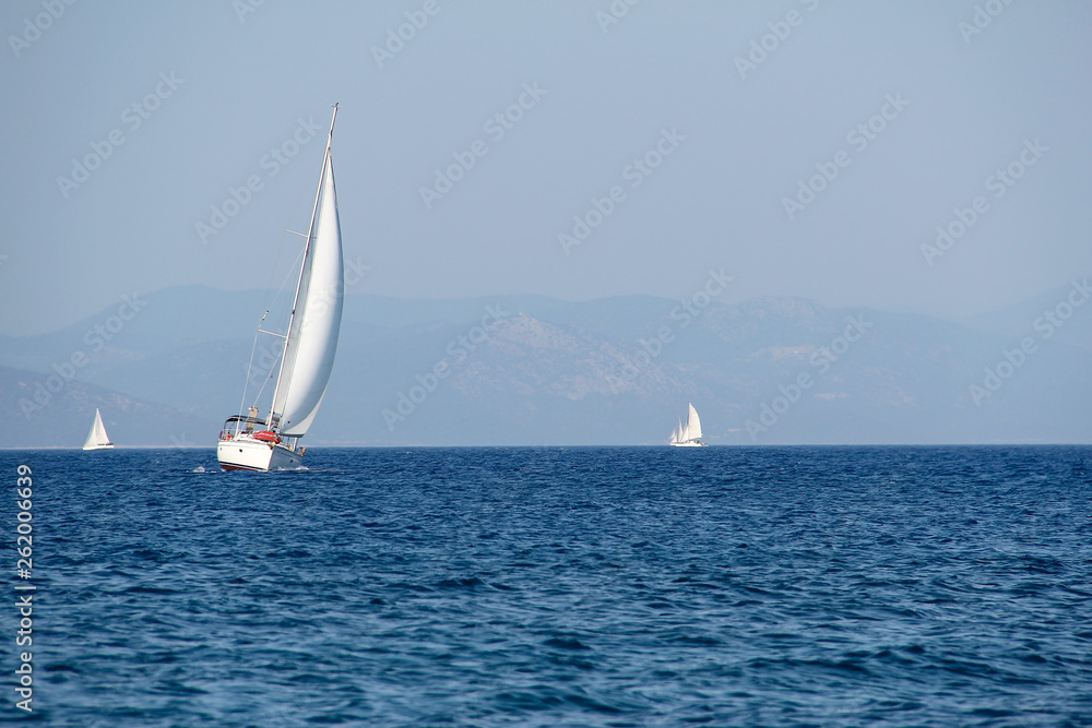 White sailboat on a background of blue sea and sky