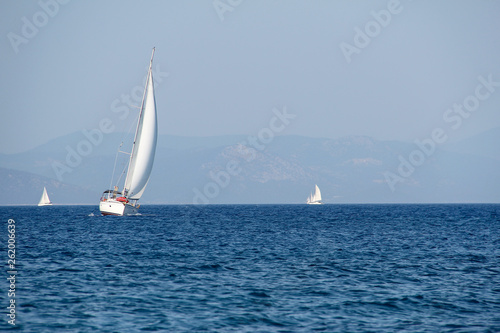 White sailboat on a background of blue sea and sky