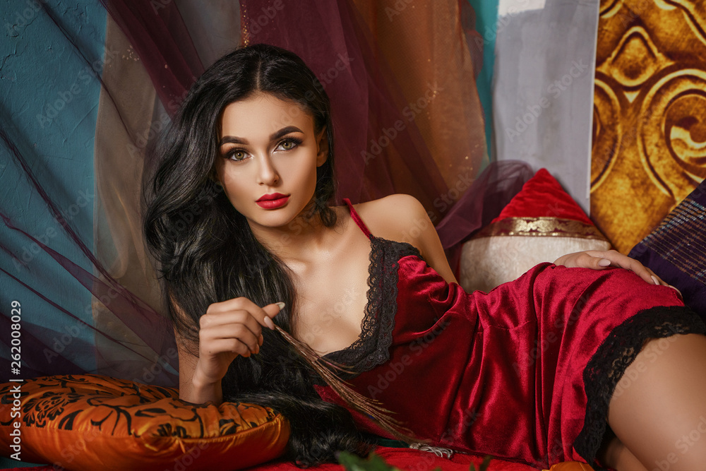 fashionable beautiful woman lies in a red negligee