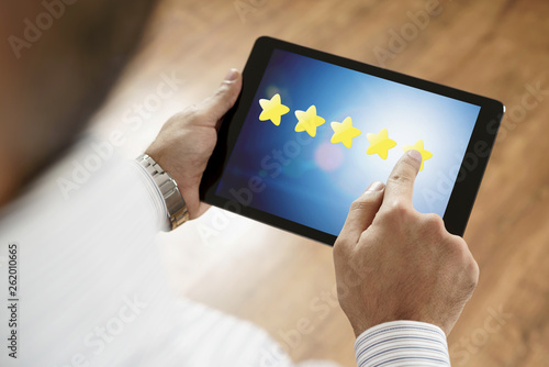 Man putting 5 stars excellent feedback on tablet screen