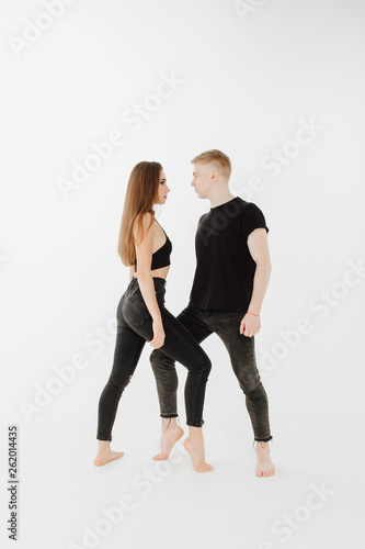 Professional Caucasian Dance Couple Stand Posing. Beautiful Brunette Slim Female Dancer Looking at Blond Male Partner. Contemporary Duet Wear Black Form Side View Isolated on White Background