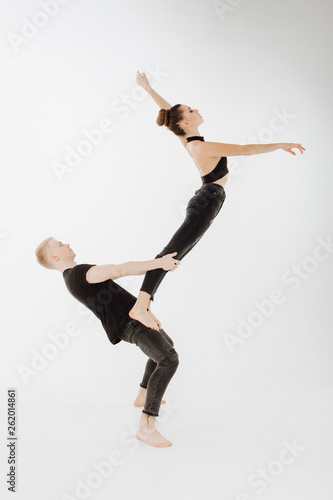 Caucasian Dance Couple Balancing High Level Pose. Man in Demi Plie, Female Dancer Stand on his Hip, Bend, do Arabesque. Young Perfomer in Black do Grase Acrobatic Lift Isolated on White Background