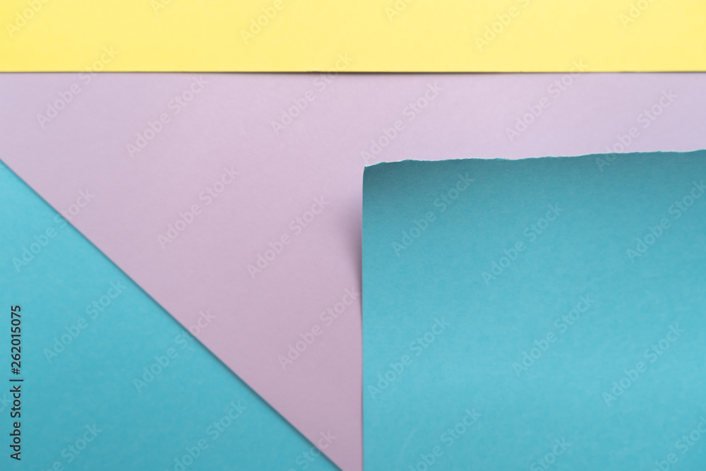 Purple-blue-yellow paper background. A piece of blue paper with torn edges, yellow stripe and blue triangle on the background of a sheet of purple paper Purple-blue-yellow paper background. A piece of blue paper with torn edges, yellow stripe and blue triangle on the background of a sheet of purple paper
