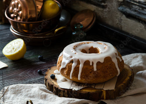 Homemade delicious bundt cake (with hole) with white glaze on top on wooden stand