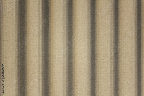 gray concrete shield with wavy relief and shadows. vertical lines. rough surface texture