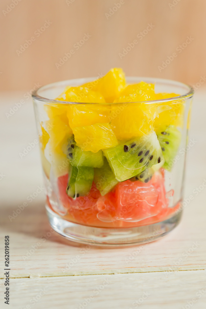 Diet Fresh tasty mix fruit salad in a glass jar on rustic wooden background. Chopped juicy oranges, kiwi and grapefruits. Diet Fresh tasty mix fruit salad in a glass jar on rustic wooden background. Chopped juicy oranges, kiwi and grapefruits.
