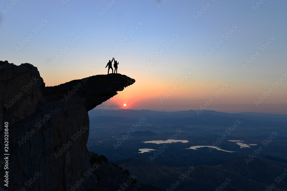 triumph of couples reaching dangerous cliffs