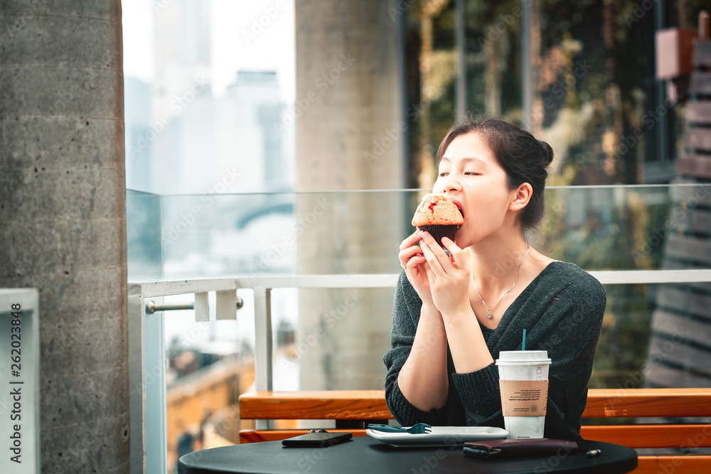 Young woman drinking coffee and eating a delicious muffin cake in cafe, Young woman drinking coffee and eating a delicious muffin cake in cafe,
