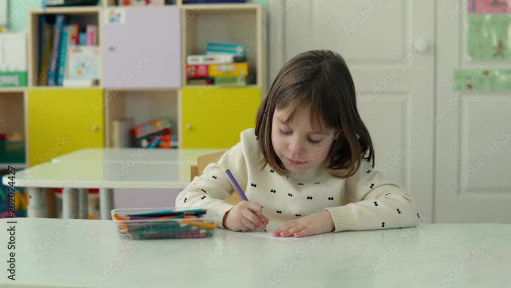 Girl preschooler in kindergarten. The girl draws with pencils. Blurred background. Girl preschooler in kindergarten. The girl draws with pencils. Blurred background.