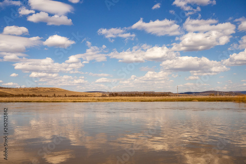 Spring flood of the river. Blue sky and white clouds. Landscape.