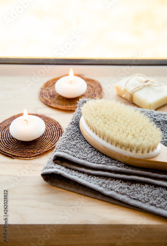 Dry brushing the skin in a pattern with a dry brush, usually before showering help reduce cellulite and remove toxins in human body. Selective focus on firm, natural bristle brush with a long handle.