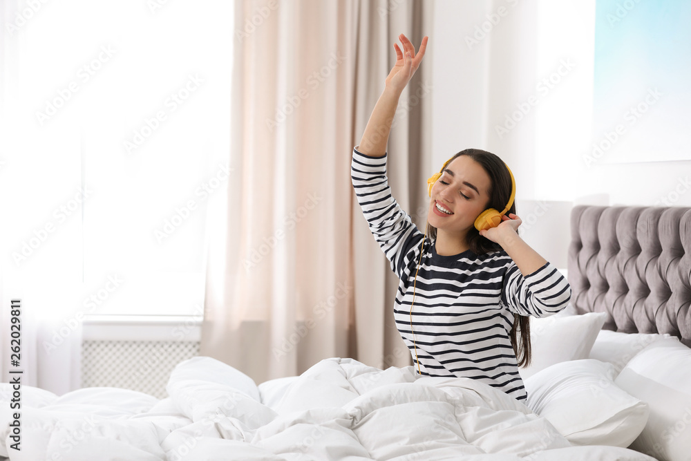 Young woman with headphones enjoying music in bed Young woman with headphones enjoying music in bed