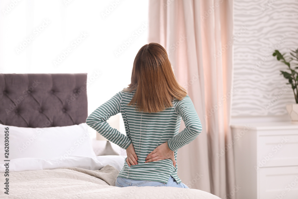 Young woman suffering from back pain at home Young woman suffering from back pain at home