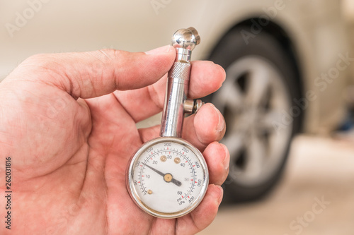 Tire gauge in hand. Blur the wheel as the background.