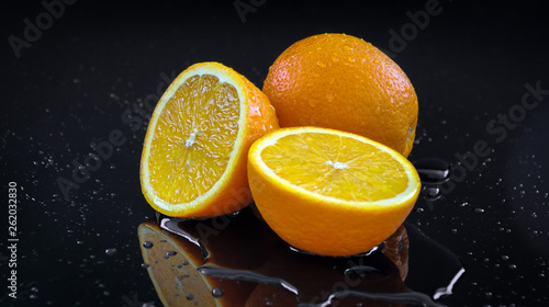 Fresh oranges on black background sliced orange water pouring on fruits